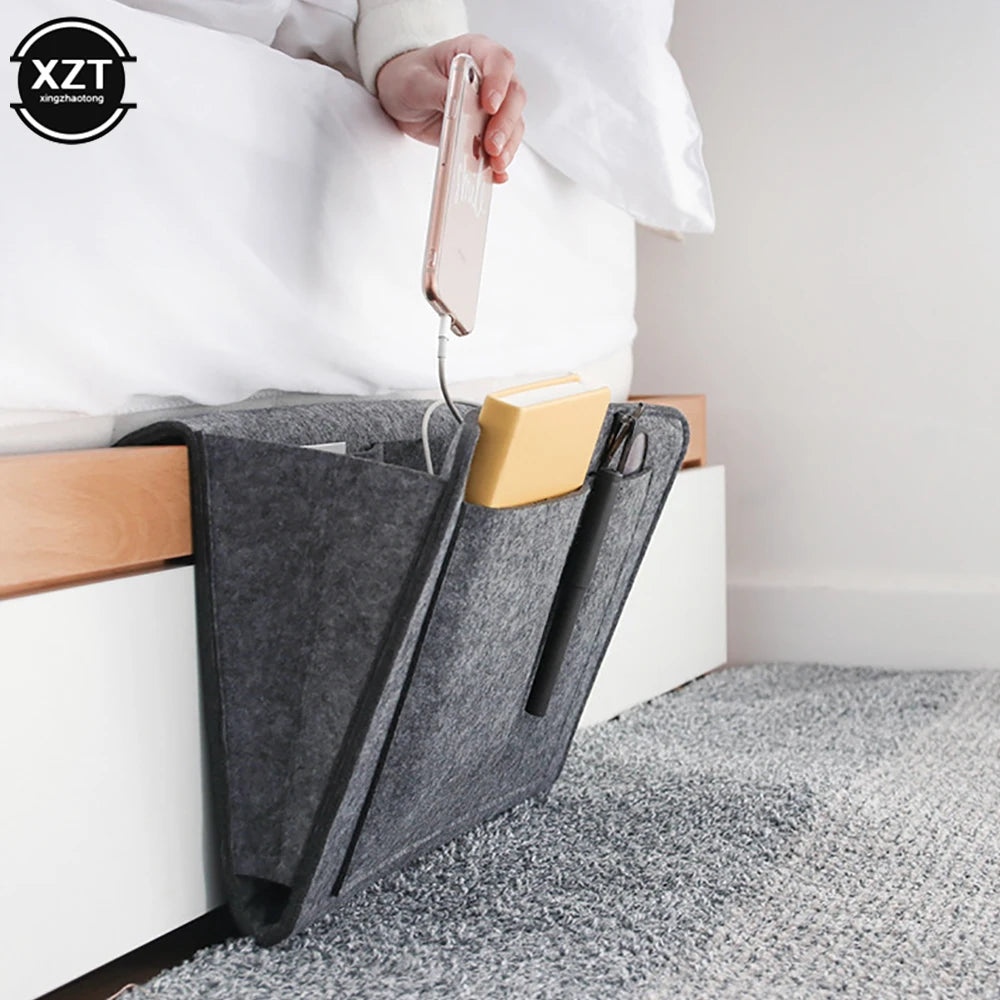 Felt bedside storage organizer in grey with pockets for phone, book, tissue box and pen; hanging over bed rail