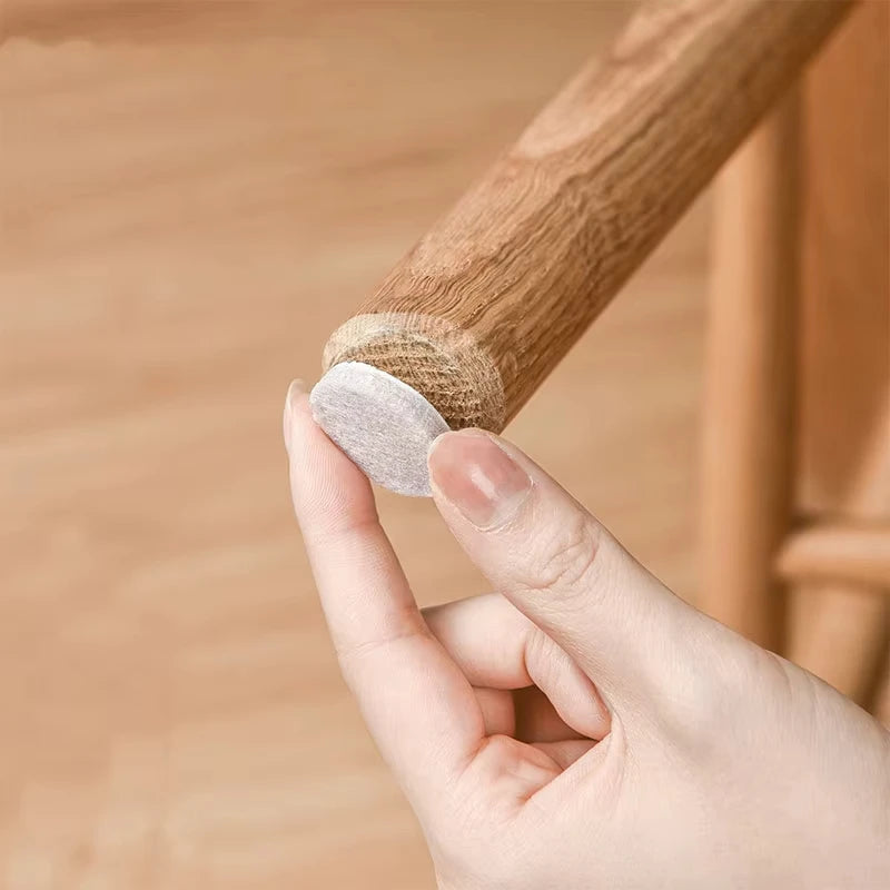 Round self-adhesive felt chair leg pad from MobilityBuy.com applied to a wooden chair leg; floor protector.
