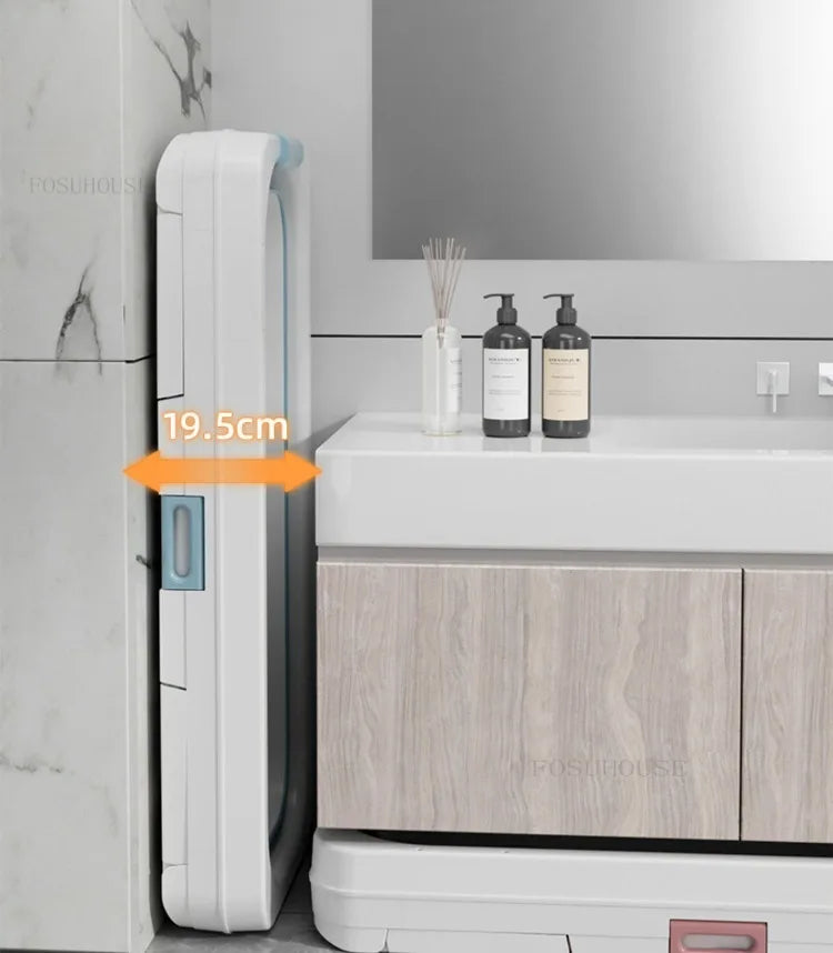 Portable folding bathtub for adults in white plastic with blue latch, shown folded upright beside bathroom vanity.